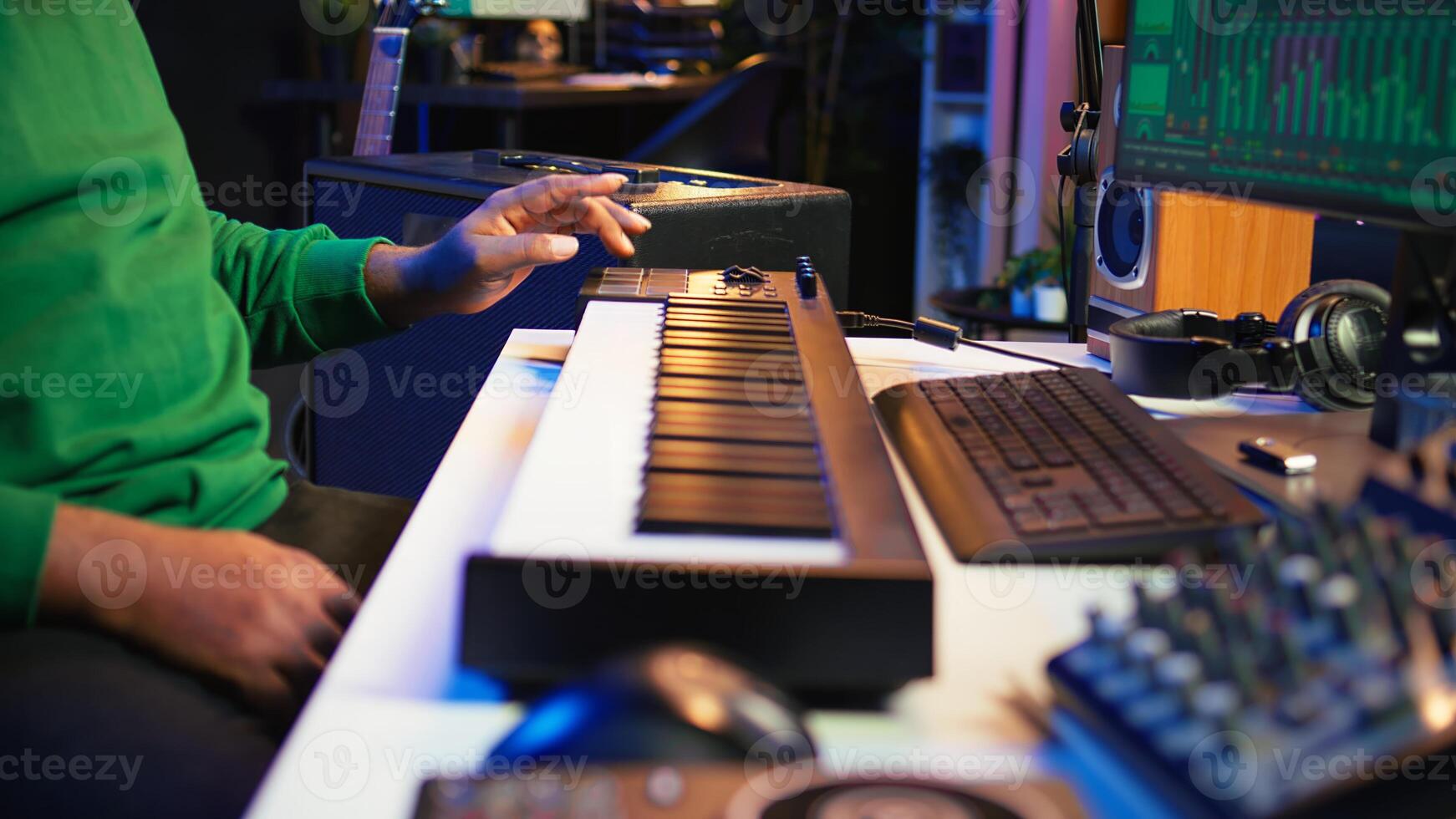 Music engineer producing song by mixing and mastering tunes on audio console, playing piano notes on synthesizer to record sounds on pc. Producer creating soundtracks with midi controller. Camera B. photo