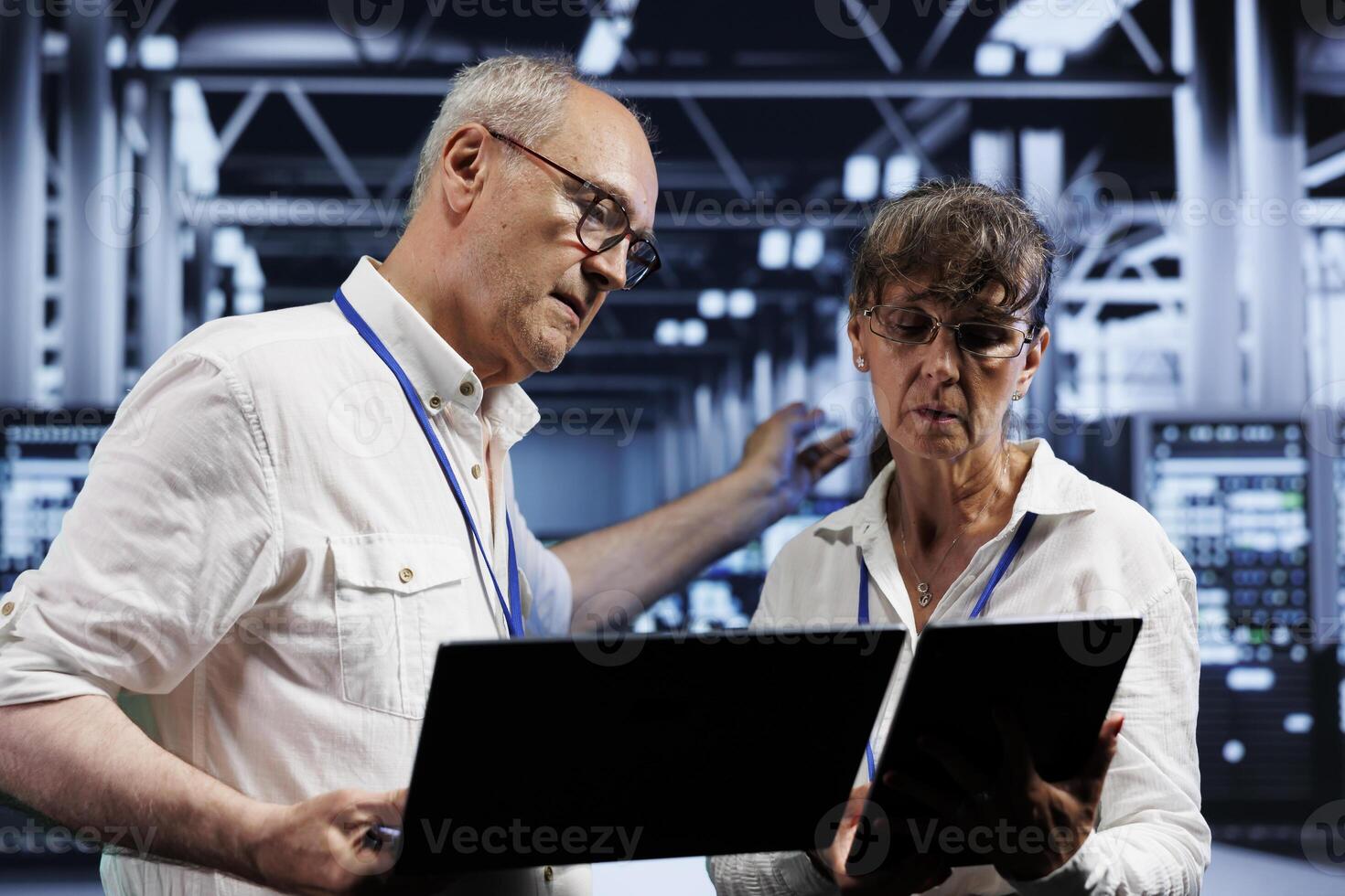 Computer scientists performing diagnostic assessments on server rigs to detect problems with data center devices. Aged specialists crosschecking checkup lists, examining for potential system defects photo