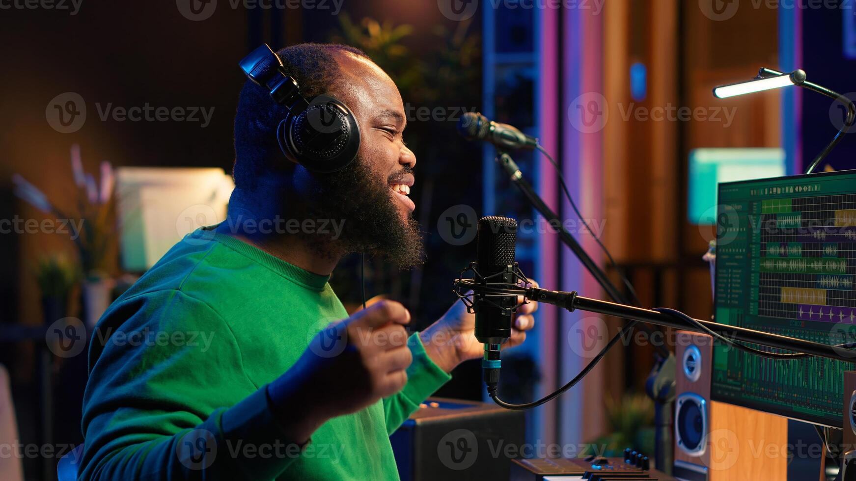 Confident songwriter performing a tune on microphone in home studio, recording his song and editing in post production. Performer artist singing aloud and using stereo equipment. Camera A. photo
