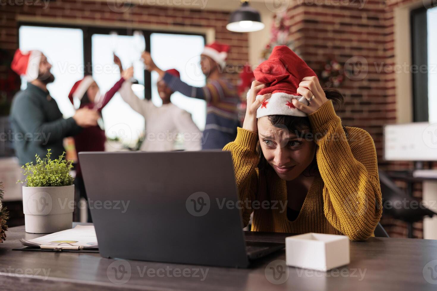Stressed unhappy woman having burnout while working on project during christmas holiday in decorated office. Frustrated overworked company employee managing workload during winter holiday photo