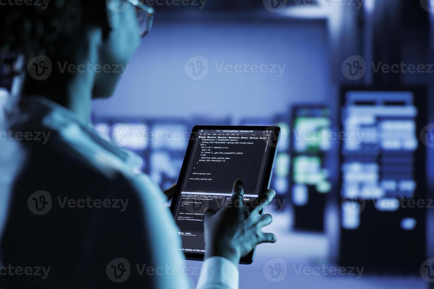 Computer operator builds firewall systems in server room housing advanced infrastructure. Facility manager runs code on tablet to upgrade data center rigs handling demanding workloads photo