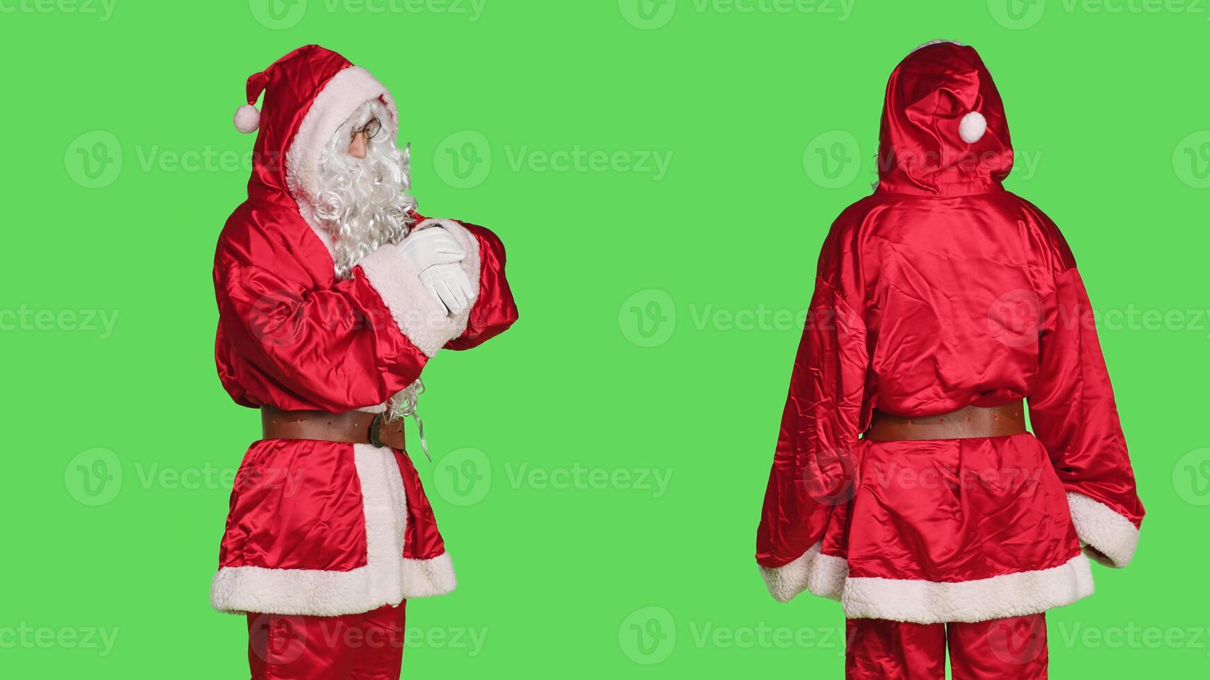 Impatient man in saint nick costume checking time on wristwatch, posing with confidence over greenscreen. Santa claus with white beard representing festive holiday celebration and waiting. photo