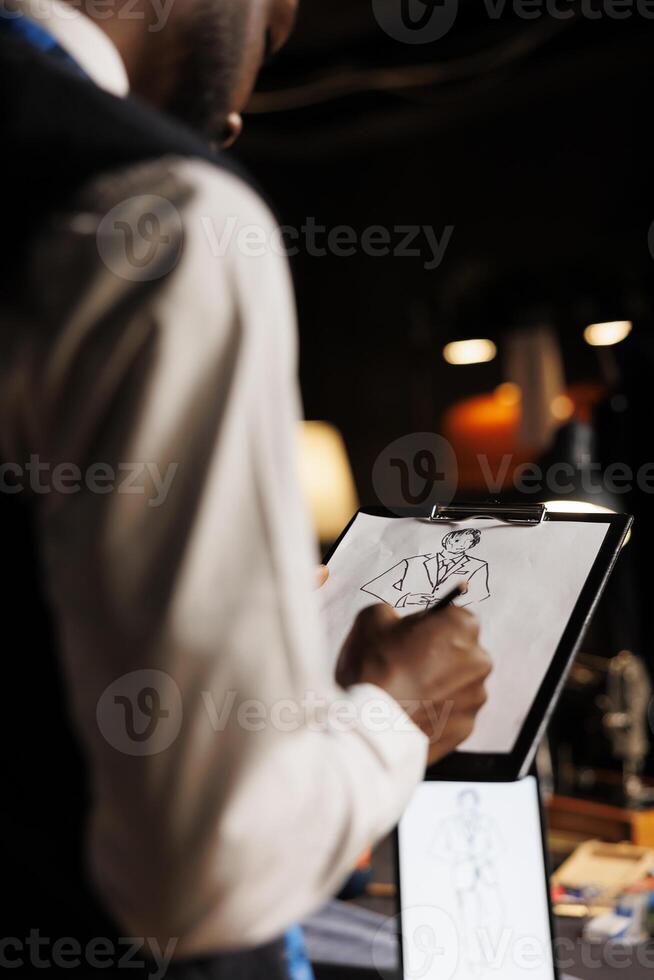 Precise fashion designer conceptualizing custom made sartorial business suit collection in tailoring studio. Experienced couturier handdrawing sketch of bespoke garment piece photo