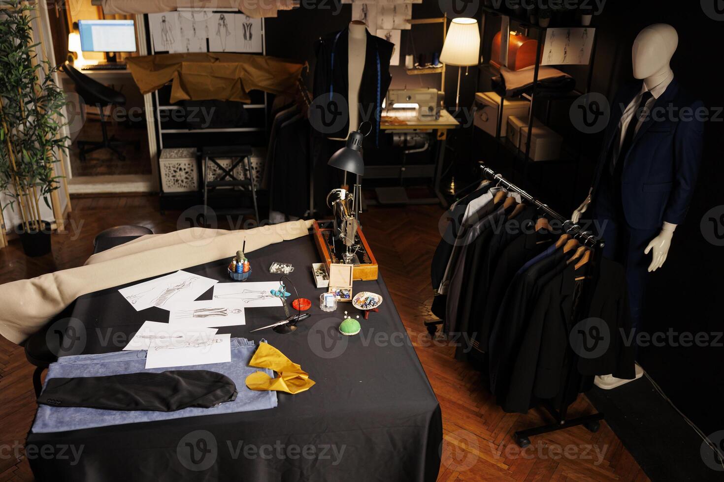 High angle shot of creative upscale tailoring studio full of bespoken sartorial suits, sketch drawings and sewing instruments on table. Professional atelier shop with premium fashion collection photo