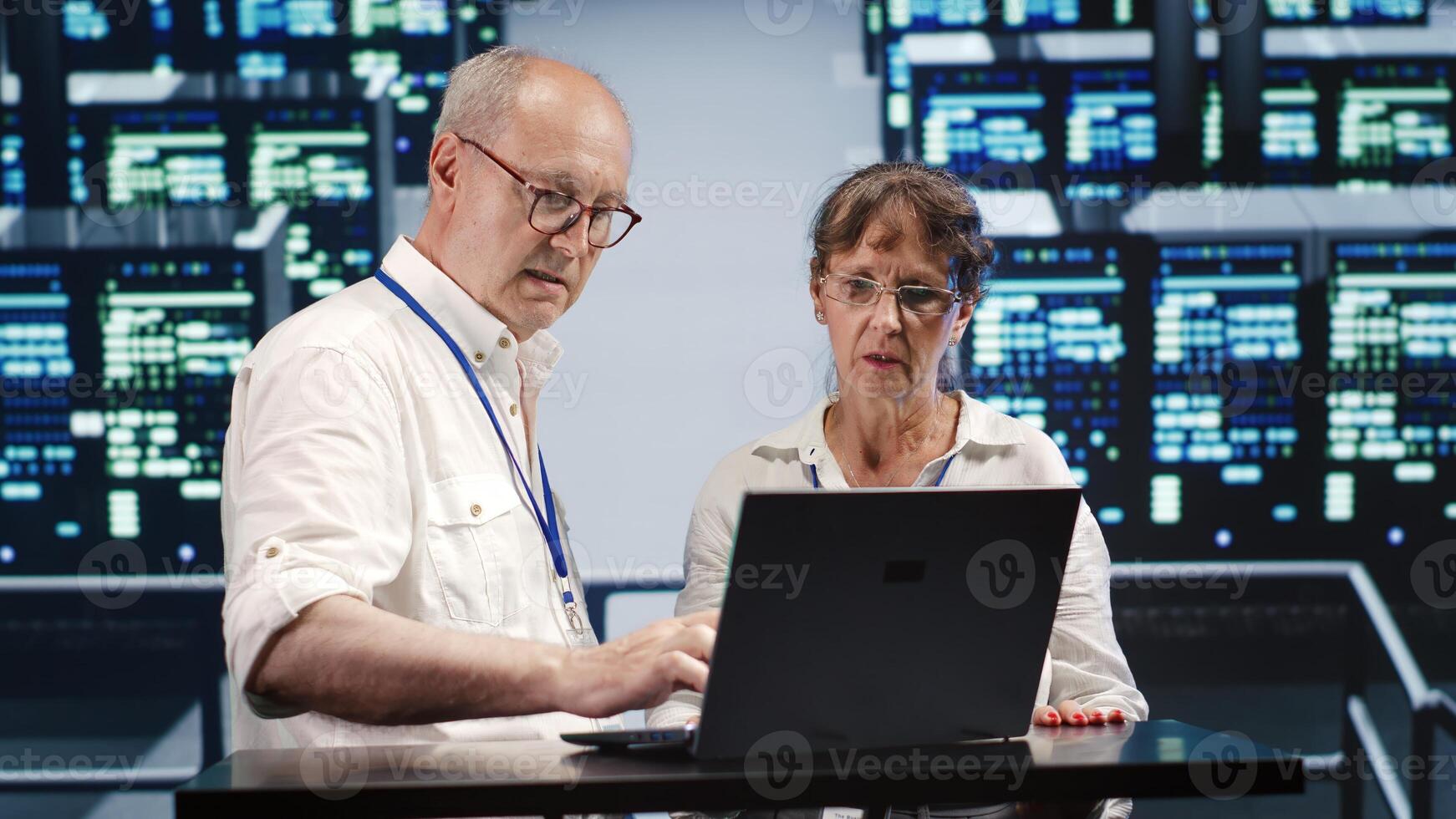 Aged coworkers looking around modern server farm, preparing to start comission on malfunctioning high tech workspace hardware clusters in order to ensure proper operations photo