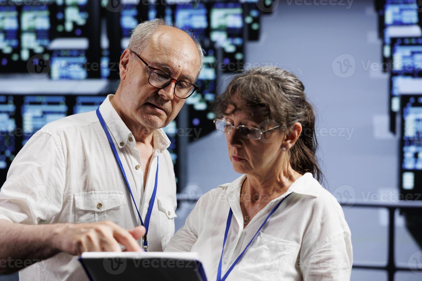 Old coworkers monitoring data center clusters, optimizing them for data processing requirements of AI applications. Skilled admins working in server room used for machine learning photo