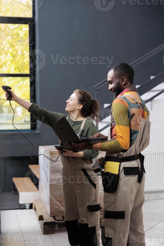 Diverse storehouse team looking at boxes scanning barcode, african american worker looking at products checklist on laptop computer. Employee working at customers order preparing packages for shipping photo