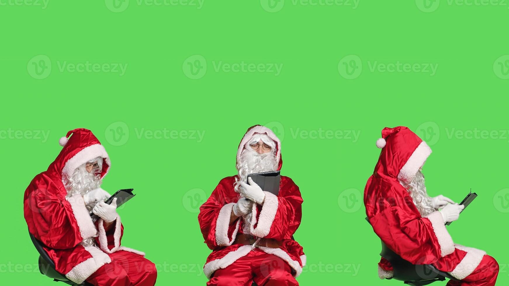 Father christmas uses tablet on chair, browsing something online before celebrating festive winter holiday. Young man in saint nick seasonal costume holding device, greenscreen. photo