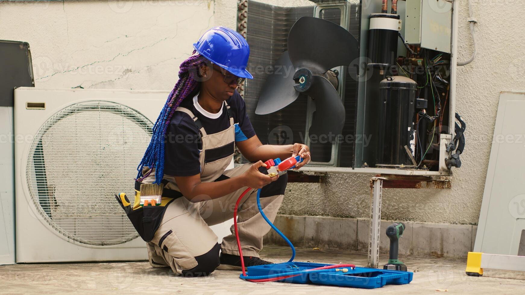 African american repairman unpacking toolbox with manifold gauges equipment needed to check freon levels. Worker commissioned by home owner, preparing for routine HVAC system maintenance photo