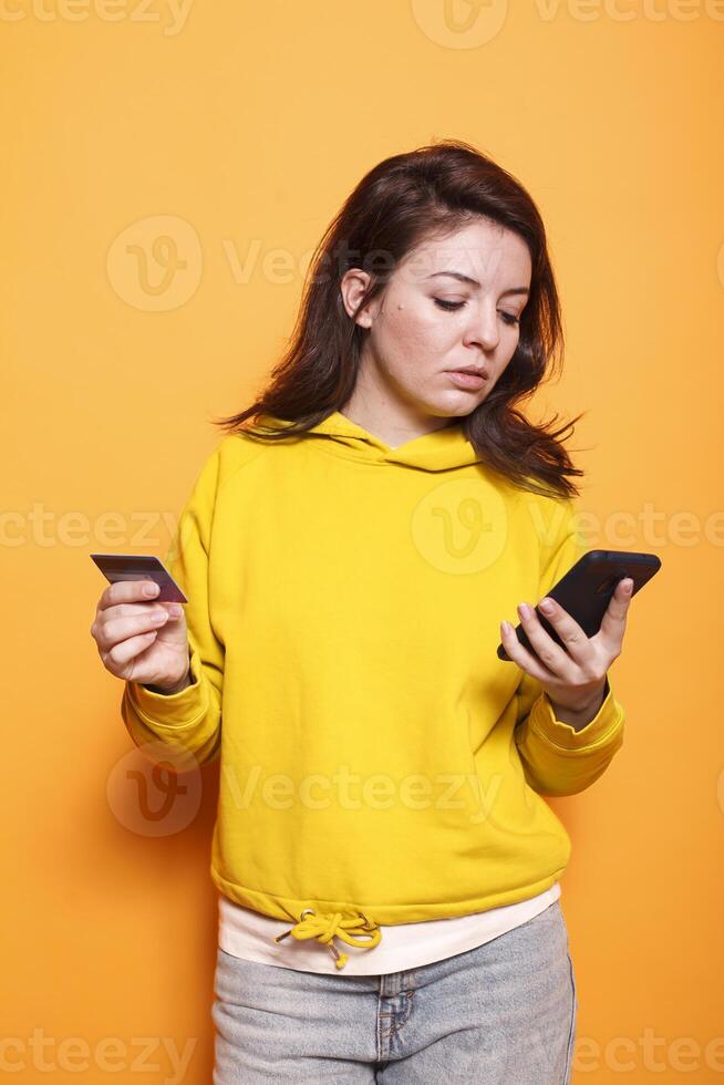 Female customer using a smartphone app to shop online with a credit card. Portrait of contemporary woman uses her phone to make a purchase using money from a bank. Shopaholic grown-up. photo