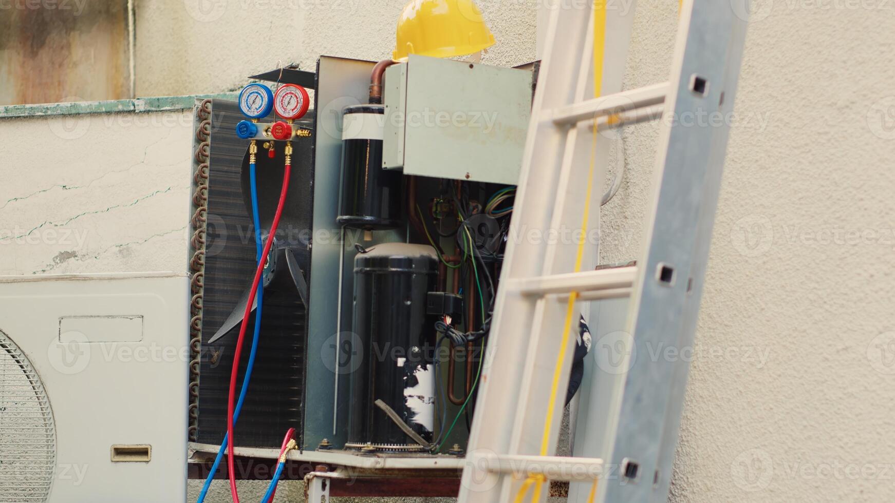 Jib up shot of damaged condenser with protection cover removed in need of fixing, with broken electric internal bits. External HVAC system waiting to be refurbished and engineering equipment photo