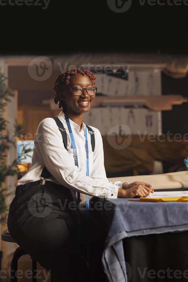 Portrait of cheerful african american fashion designer entrepreneur working in minority owned atelier shop business. Happy couturier creating sartorial outfits for upcoming comission photo
