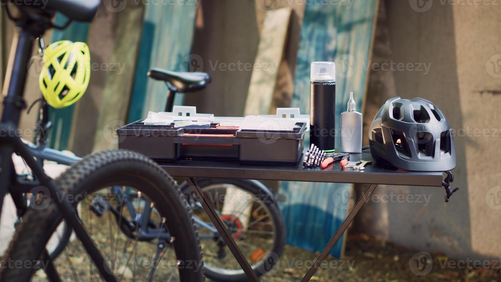 View of professional toolbox placed on table near other tools and helmet ready for bike maintenance outdoors. In yard, close-up of different specialized tools and bicycle helmet positioned on table. photo