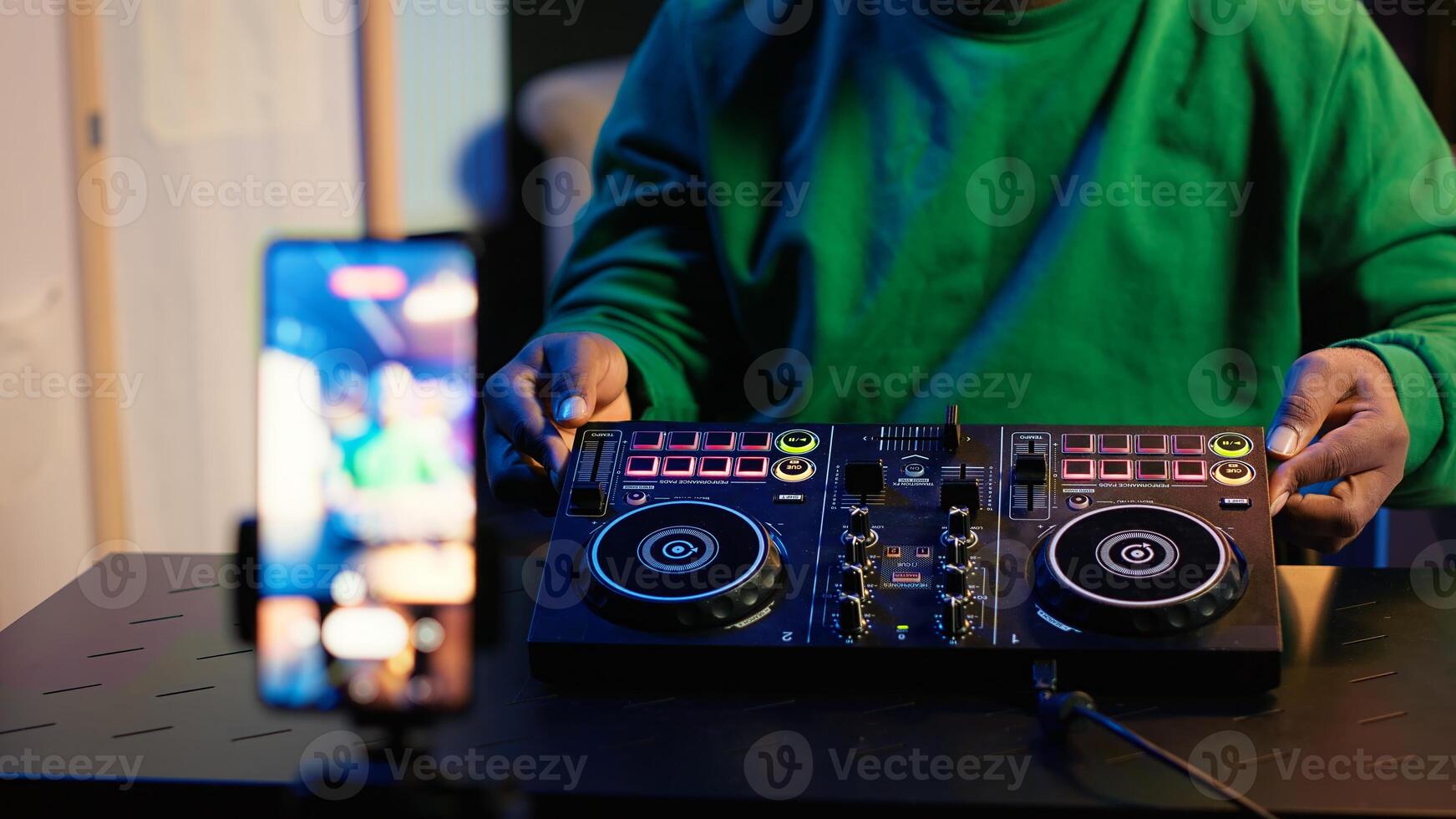 Skilled audio engineer teaching online mixing tunes lessons by using smartphone on tripod to record himself in home studio. Producer hosting a master class with soundboard console gear. Camera A. photo