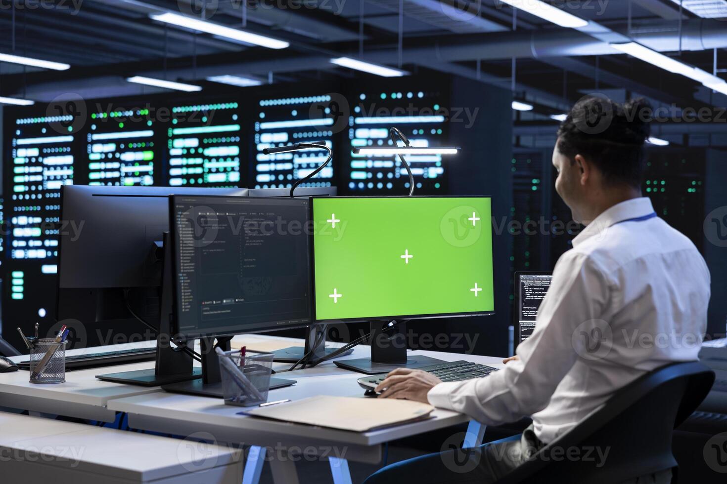 Programmer in data center using green screen computer to check for server performance issues. IT professional in server hub fixing errors slowing down hardware using mockup desktop PC photo