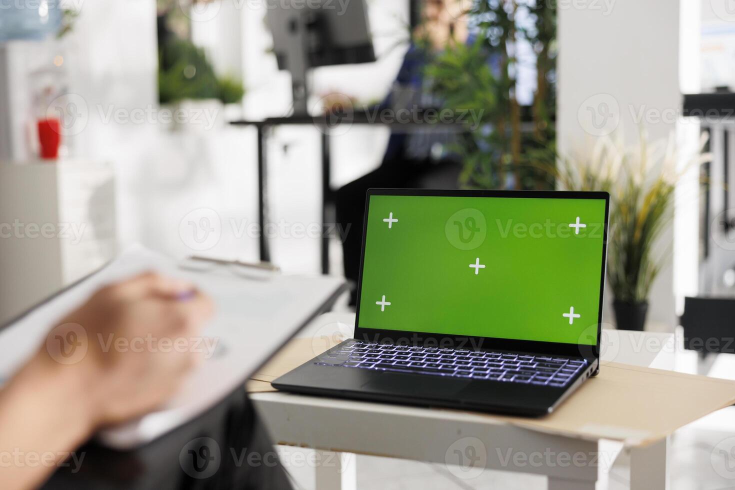 Laptop with chroma key green screen in coworking space for business presentation mock up. Corporate portable computer with blank display in modern green open space office photo