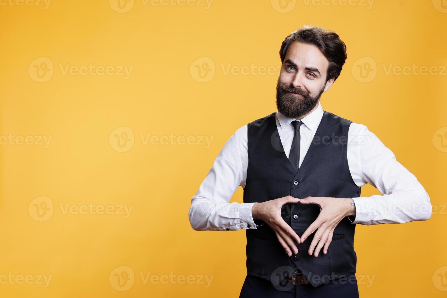 Person doing heart shaped sign on camera, expressing his honest emotions and romantic feelings with gesture. Young man in love showing true sentiments, romance symbol in studio. photo