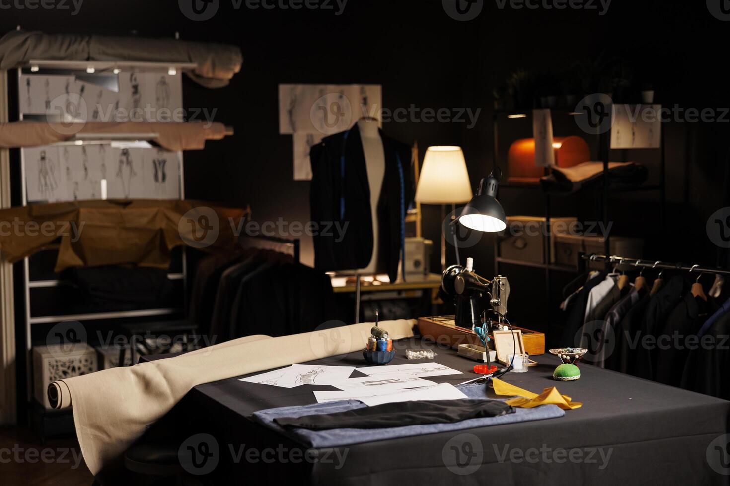 Creative atelier shop workspace where premium fashion collections are being manufactured. Professional tailoring studio full of bespoken elegant suits, sketch drawings and sewing instruments photo