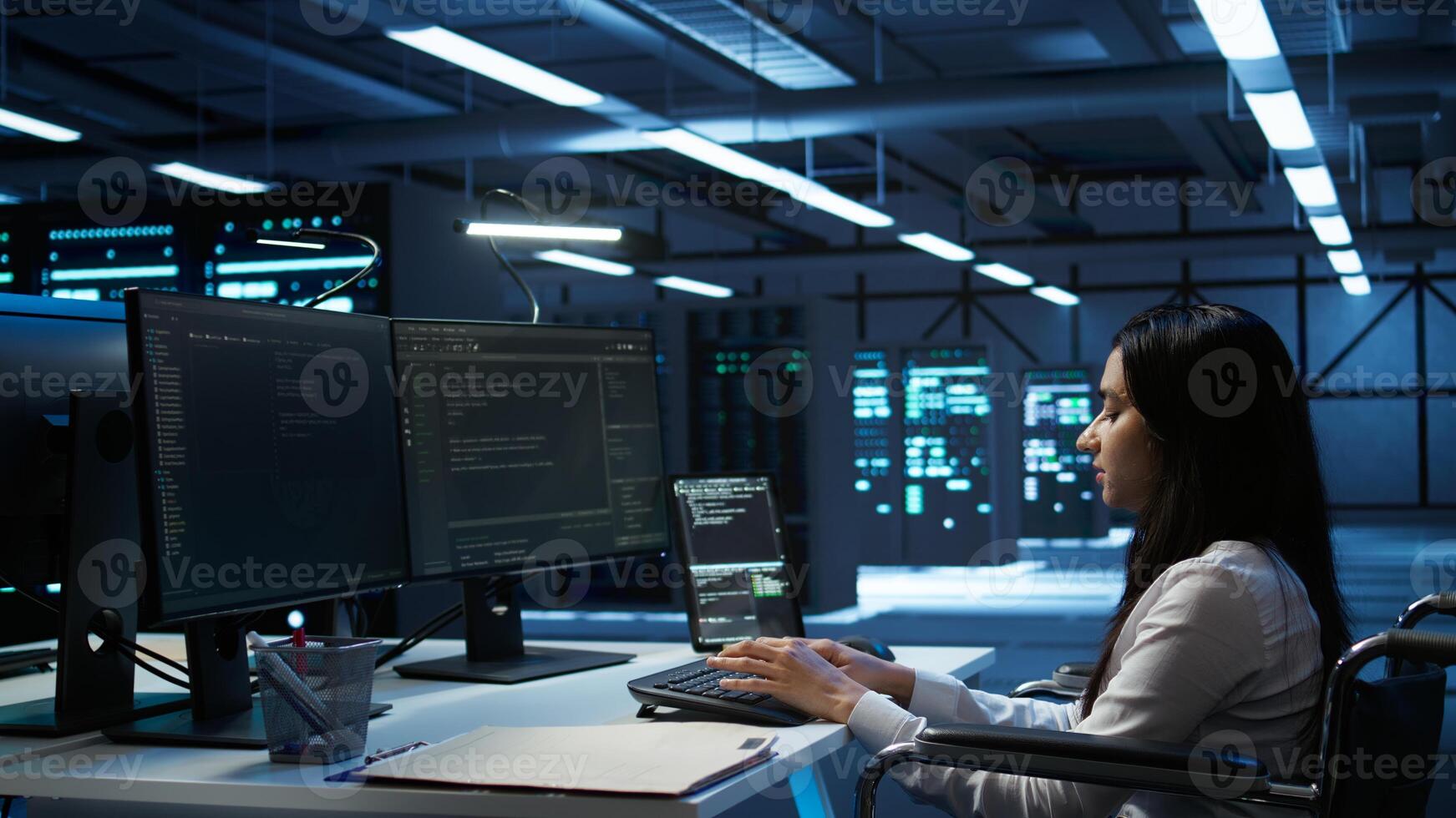 System administrator in wheelchair overseeing data center using computer, ensuring system can handle networking tasks. Person with paraplegia in server room tracking network traffic with PC photo
