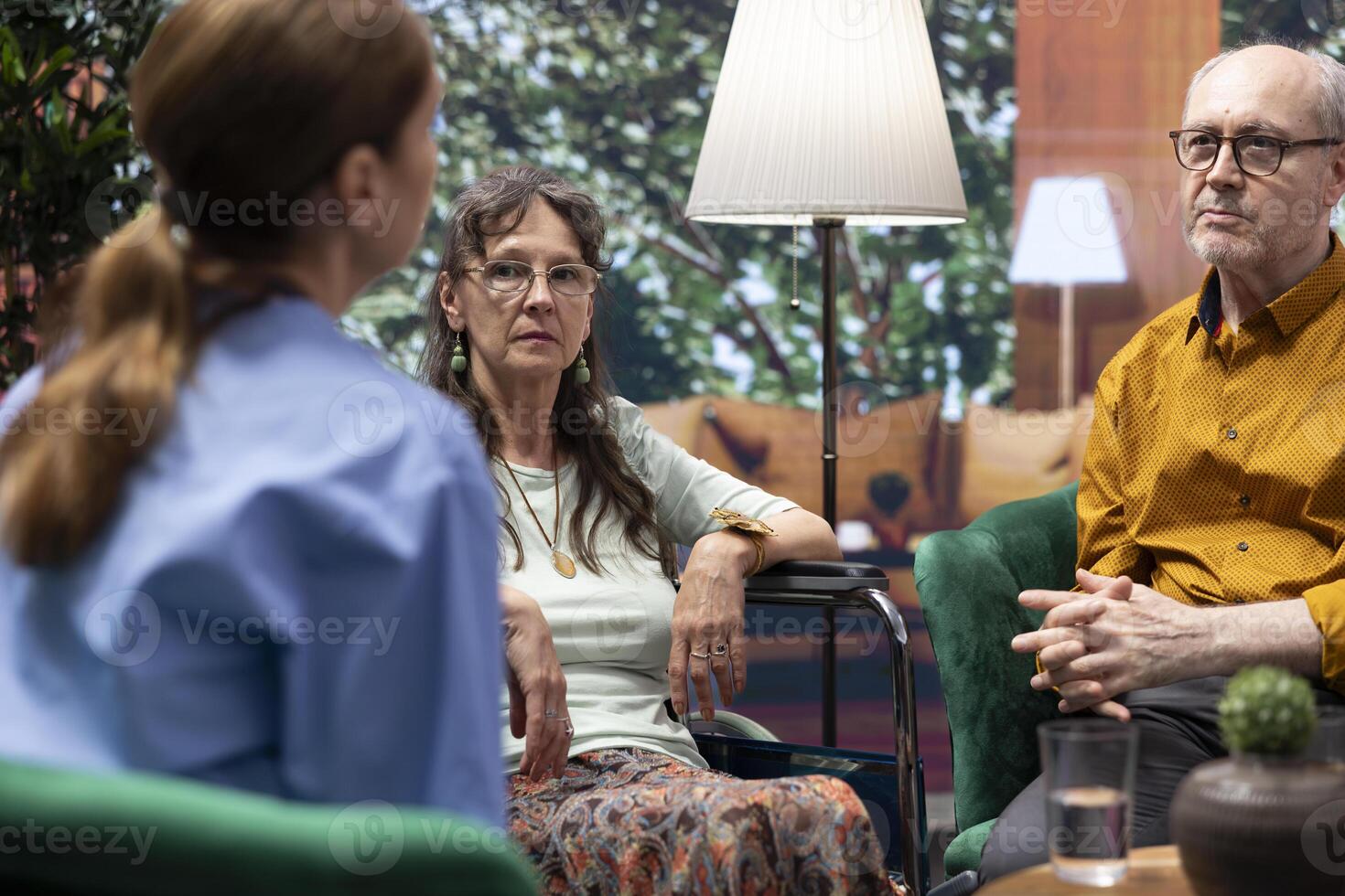 Elderly woman wheelchair user asks nurse for medical advice and pills during home visit, assistant explaining the diagnosis and prescribing necessary medication for wellness and recovery. photo