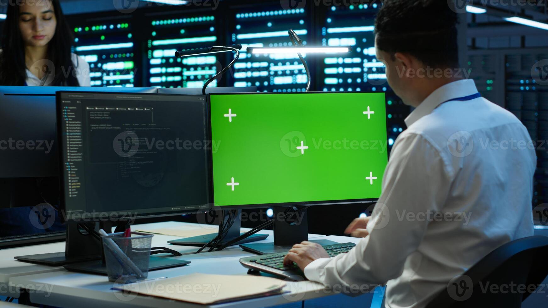Technician using mockup computer in data center, managing servers, operating systems. Expert in server hub using green screen PC to ensure networks are secure and functioning properly, camera A photo