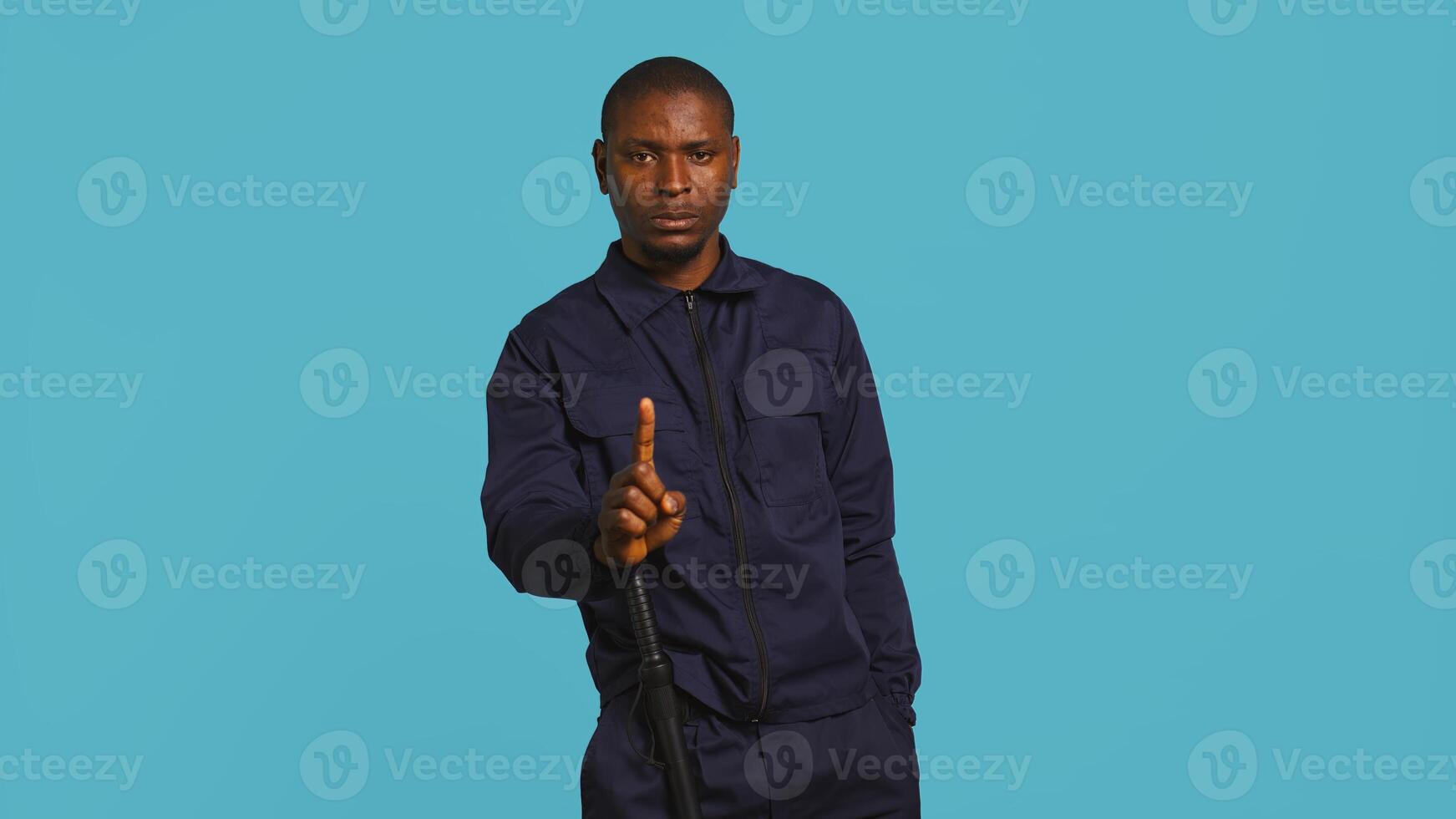 Security guard doing no gesturing with finger, prohibiting public access in restricted area. Portrait of stern bodyguard barring people from entering place, studio background, camera B photo