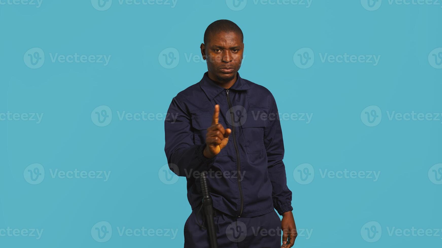 Portrait of security agent doing no gesturing with finger, refusing people entry while securing assigned post. Guardian does disapproving hand gesture, handling security breaches, camera B photo