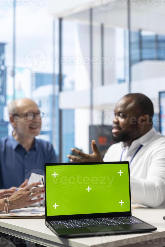 Senior couple exploring various pension plans next to green screen with financial advisor in modern office. Broker expert discussing with old people about their life savings. photo