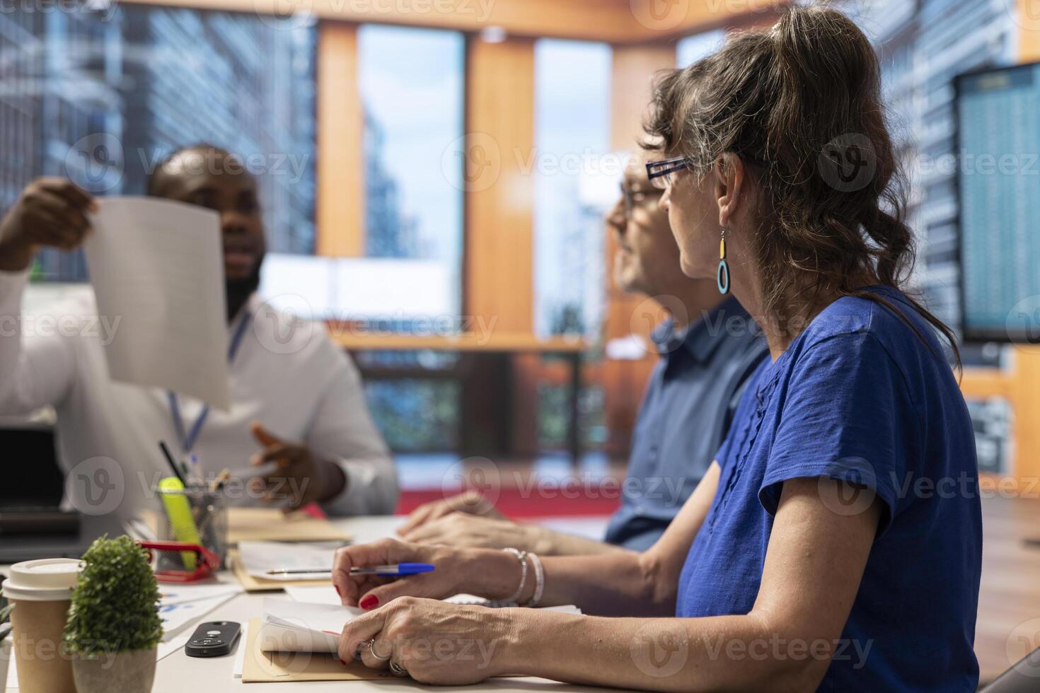 Senior woman reading banking contract terms in a meeting with broker, negotiating about retirement packages in modern office. Old people consulting with financial advisor for advice. photo