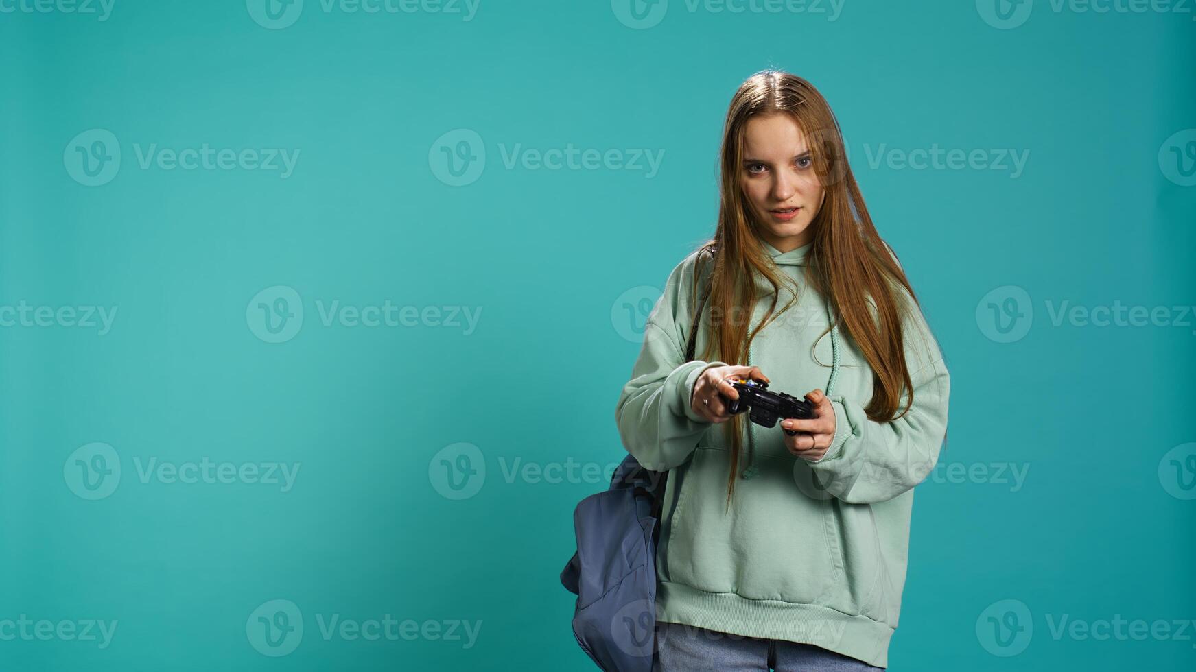 Euphoric woman playing intense gaming console game, celebrating win, studio background. Ecstatic young girl using controller, excited after being victorious in videogame, camera B photo
