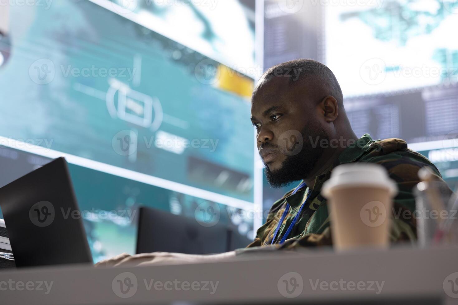 Secret service expert in an advanced command post manages reconnaissance and intelligence gathering activity, interprets real time data. IT analyst in base of operations with big screen. photo