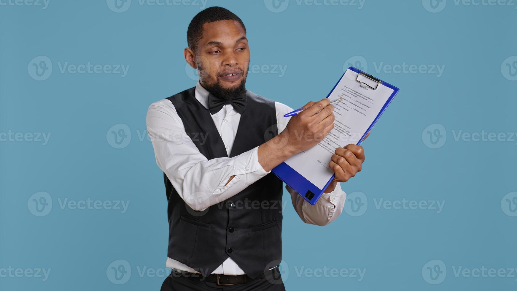 Hotel concierge showing the check in forms for registration at the five star resort, needs a signature for legal process and formalities. Bellhop receptionist welcoming guests. Camera B. photo