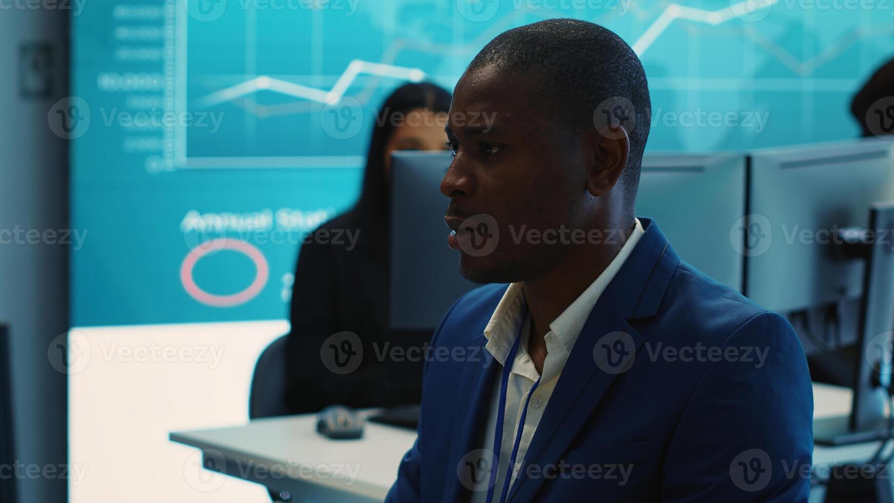 Chief executive officer reviewing project details about achieving business goals, establishing resource allocation. Administrator works in a firm monitoring room with big screen. Camera A. photo