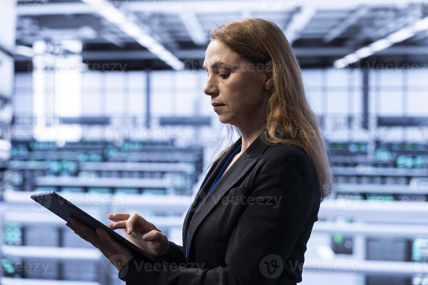 Data center software developer ensuring safety and security of database using tablet. Cybersecurity professional in server farm preventing unauthorized access posing risks for company photo