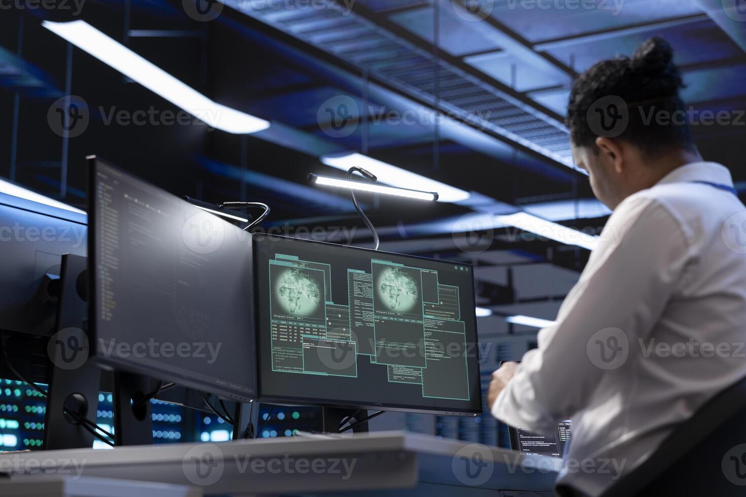 Software developer using computer in server room to support global connections using their hardware. IT expert inspecting data center hardware supporting worldwide network using PC photo