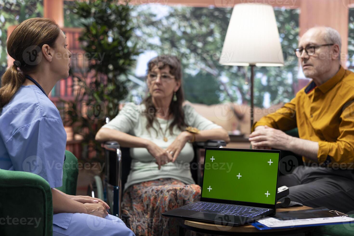 Nurse discussing with elderly people at their home next to isolated chroma key screen, giving medical advice and recommending healthcare treatment on prescription. Senior support. photo