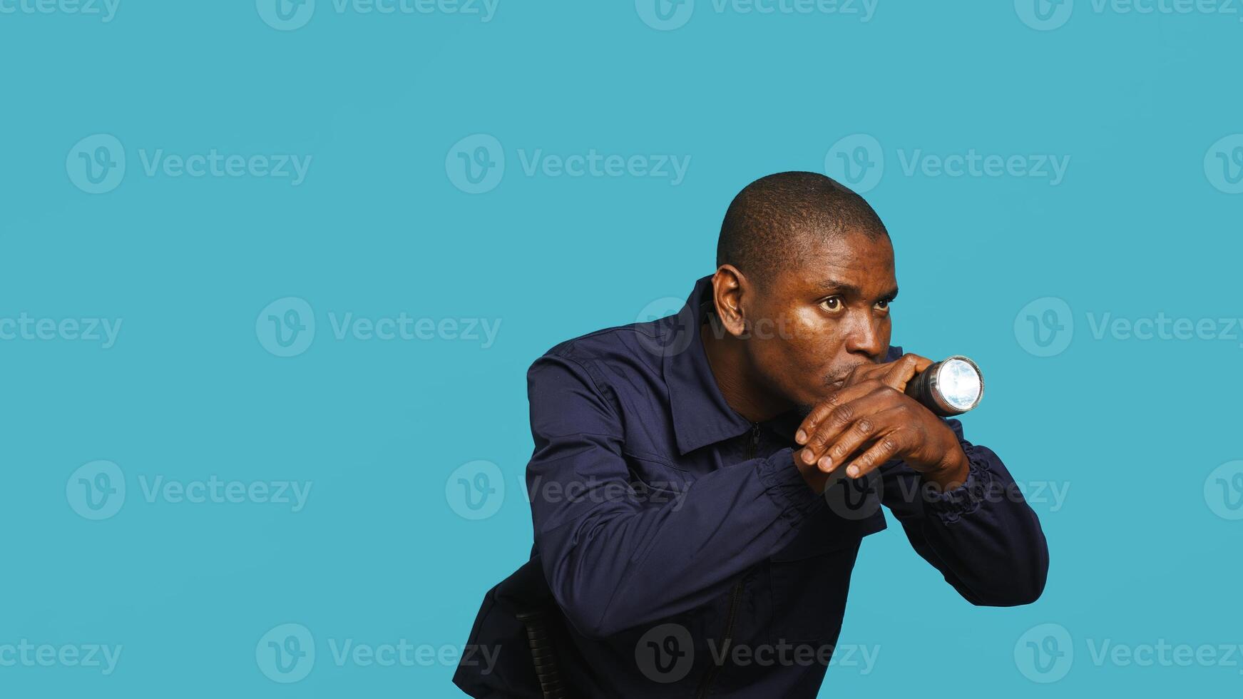 Portrait of security staff member tasked with evicting trespassers turns on flashlight. Patrolling agent maintains secure environment with lantern device, spotting people, studio background, camera A photo