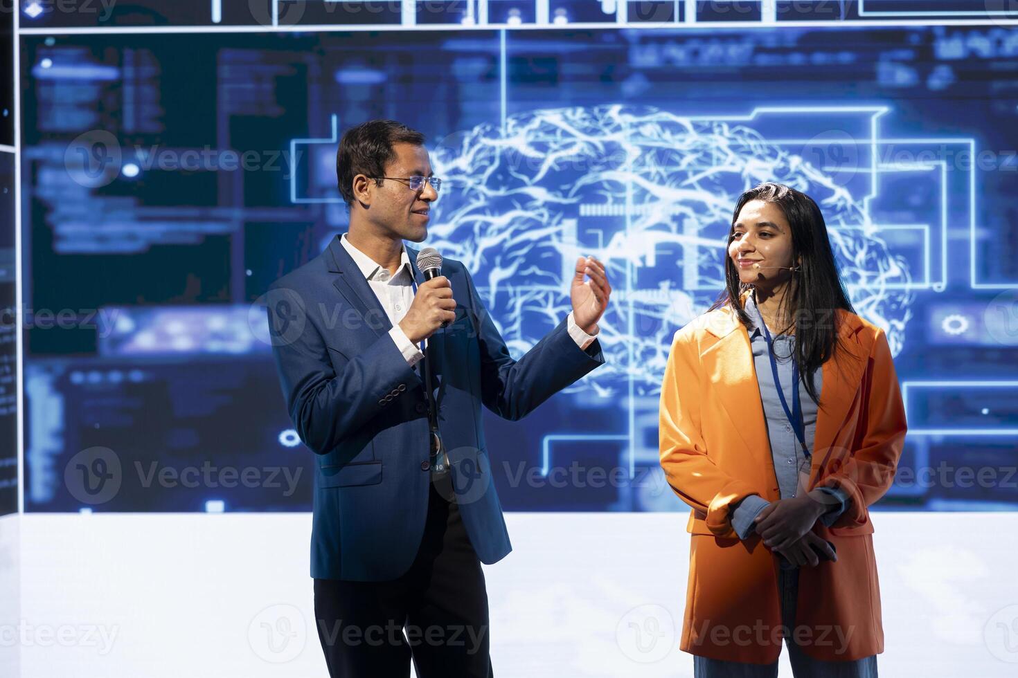 Smiling tech startup managers offer latest AI services during tech summit. Upbeat businesspeople using mic to do presentation for business investors interested in artificial intelligence photo