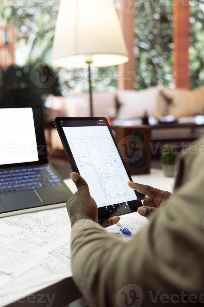 Business owner analyzing blueprints and layouts for a new office space relocation plan, investing in a creative workspace property leasing. Drafting architectural layouts at home desk. photo