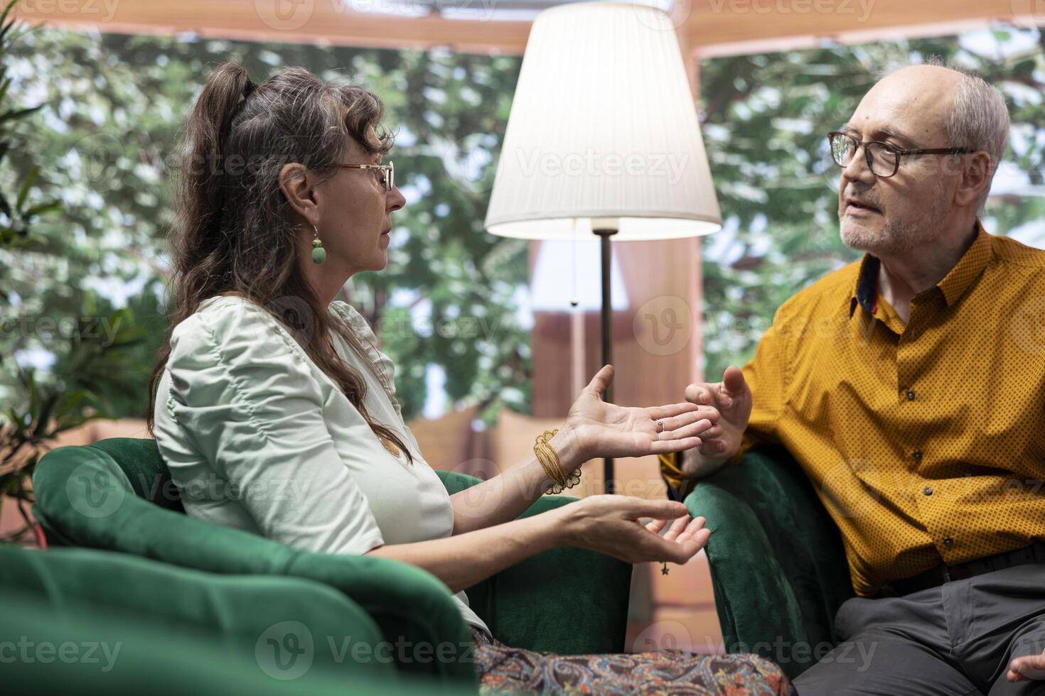 Senior husband and wife smiling and enjoying a cheerful conversation, feeling good in their free time and relaxing at home. Embracing aging process and longevity together with joy. photo