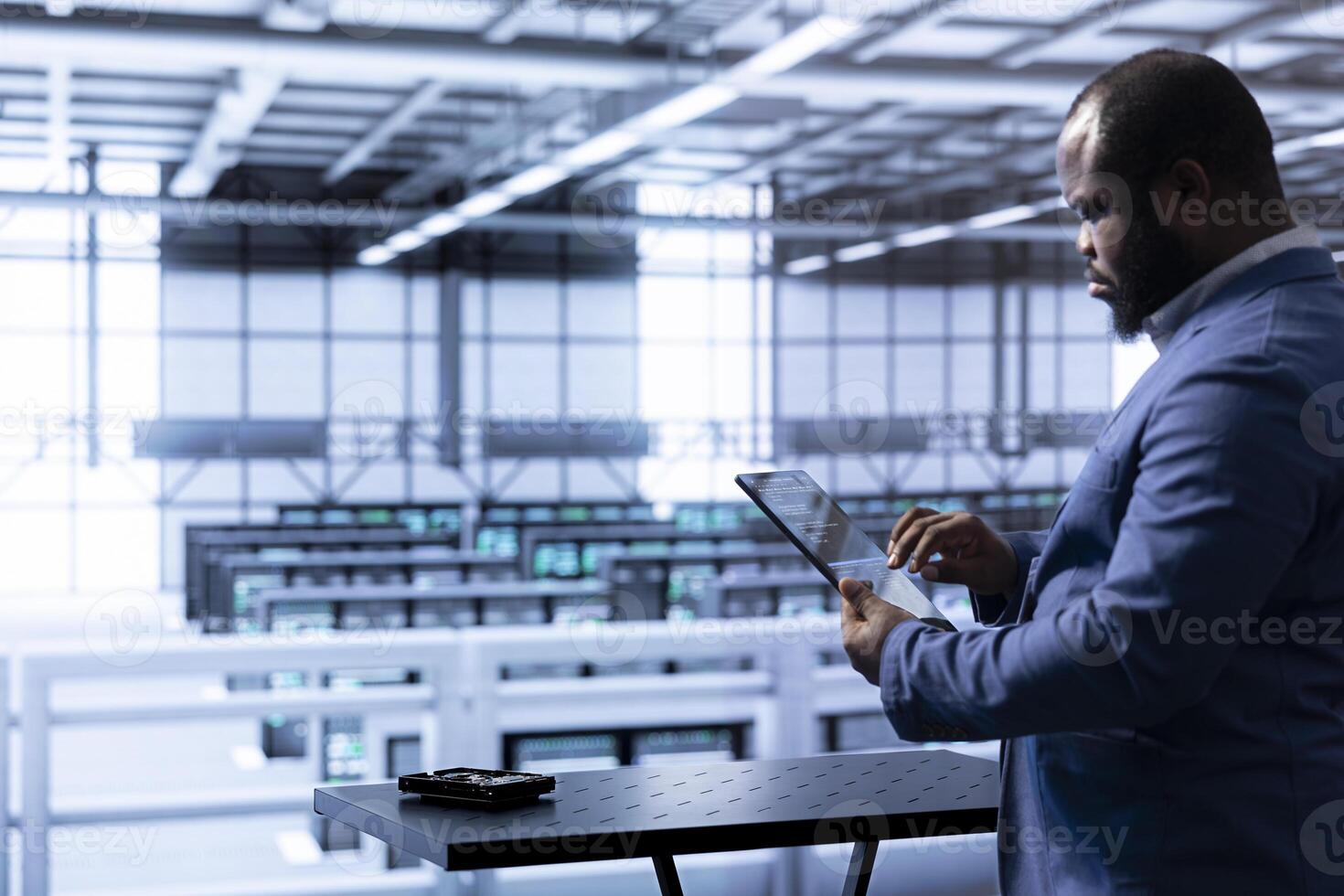 Engineer in data center using tablet to identify and solve technical issues related to data center infrastructure. IT professional managing, maintaining and securing server room environment photo