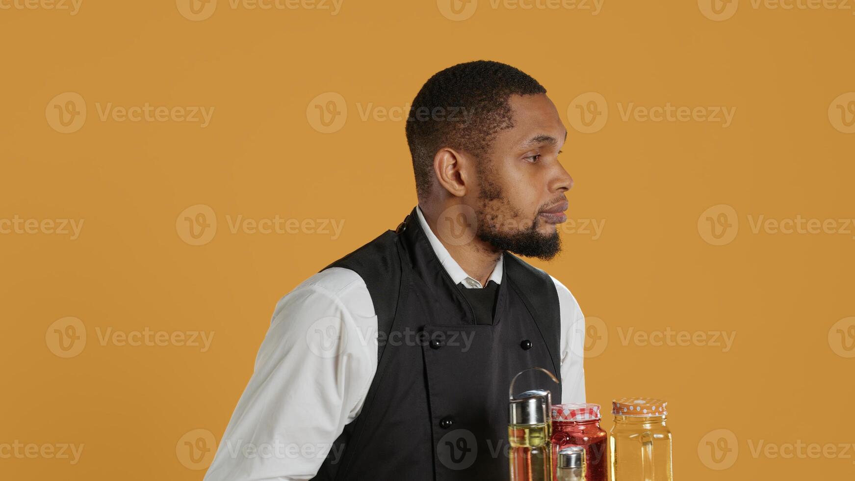 Waiter bringing drinks in glasses on a tray for clients at a table, serving lemonade to customers before their dinner. Professional staff serving people at a five star restaurant. Camera A. photo
