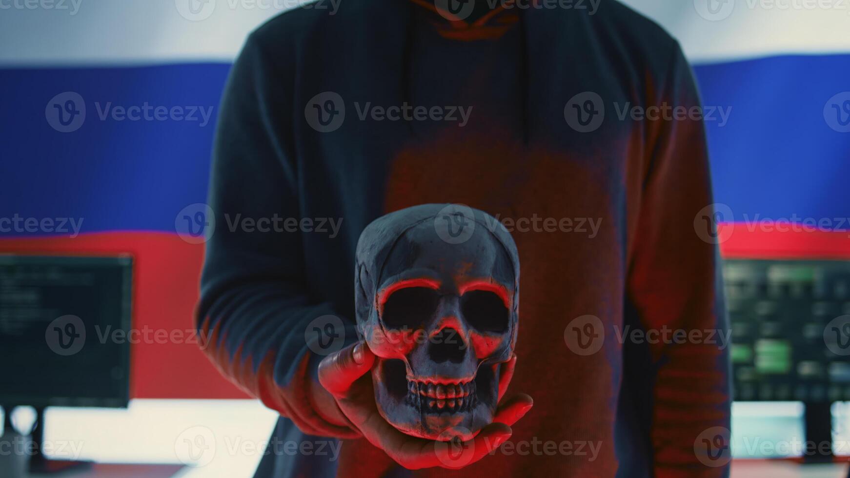 A maniacal russian hacker creating cyber threat alert by holding a skull as concept of cyber espionage and malicious code. Illustration warning of cyber security risks, evil harmful scam. Camera B. photo