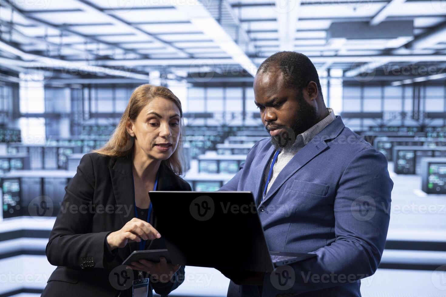 Team of programmers in server room using laptop to implement and maintain security measures, protecting systems from unauthorized access. Data center coworkers doing hardware maintenance photo