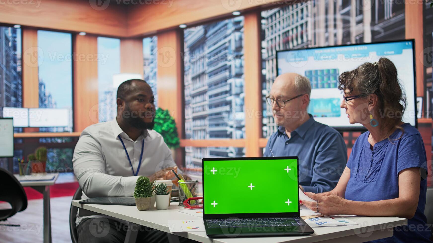 Senior people discussing with broker about securing a pension option, having a copy space mockup on laptop in office. Old clients choosing a retirement plan for life insurance. Camera B. photo