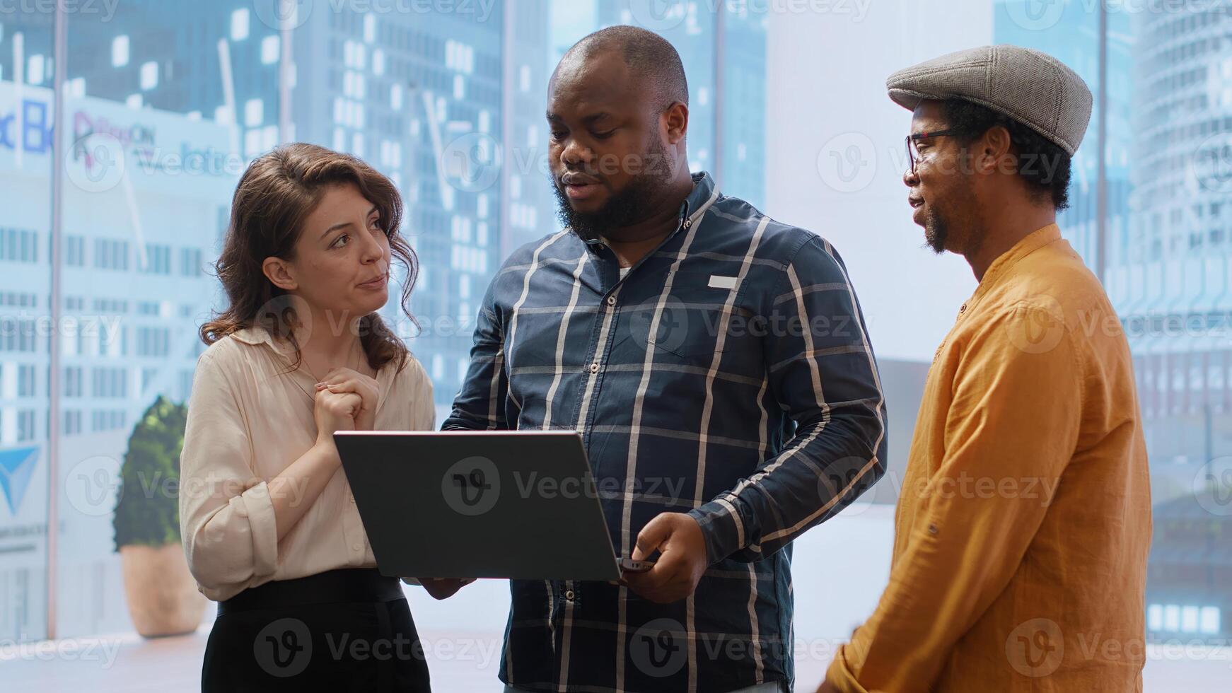 Real estate broker presenting a new high class office space to clients, discussing blueprints using a tablet during the office tour. Planning investment strategy involving property. Camera B. photo