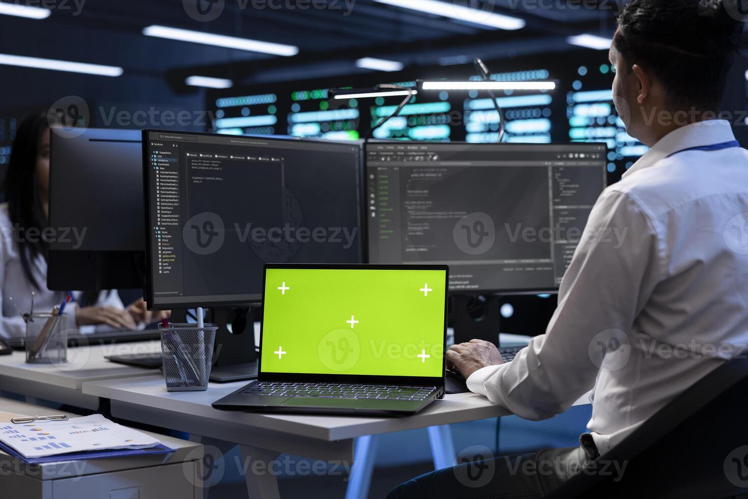 Programmers colleagues using mockup laptop to check server clusters configuration settings. Specialists checking event logs in monitoring software on green screen notebook in data center photo