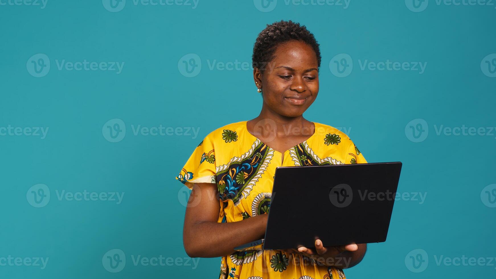 Thoughtful woman browsing websites on a laptop in studio, connected on internet network to check social media online pages. Young adult holding a wireless pc to work on freelancing. Camera A. photo