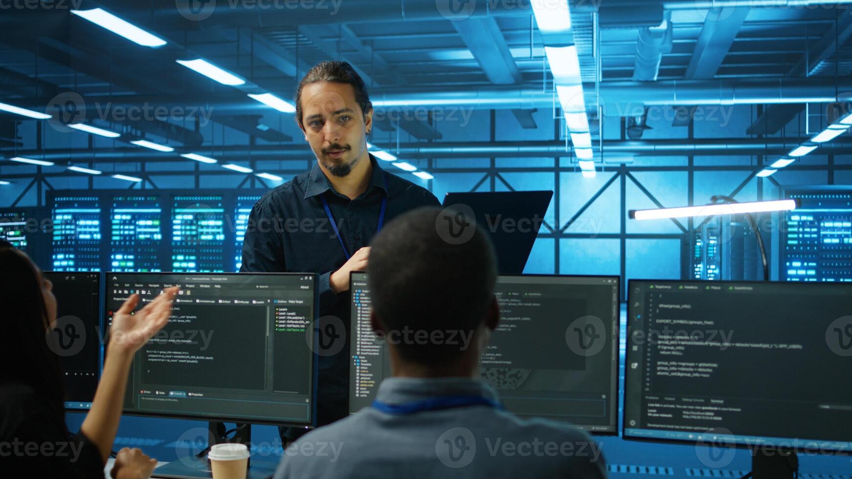 Manager supervising multiethnic team working in data center ensuring optimal performance. Supervisor and employees monitoring energy consumption across server rigs components photo