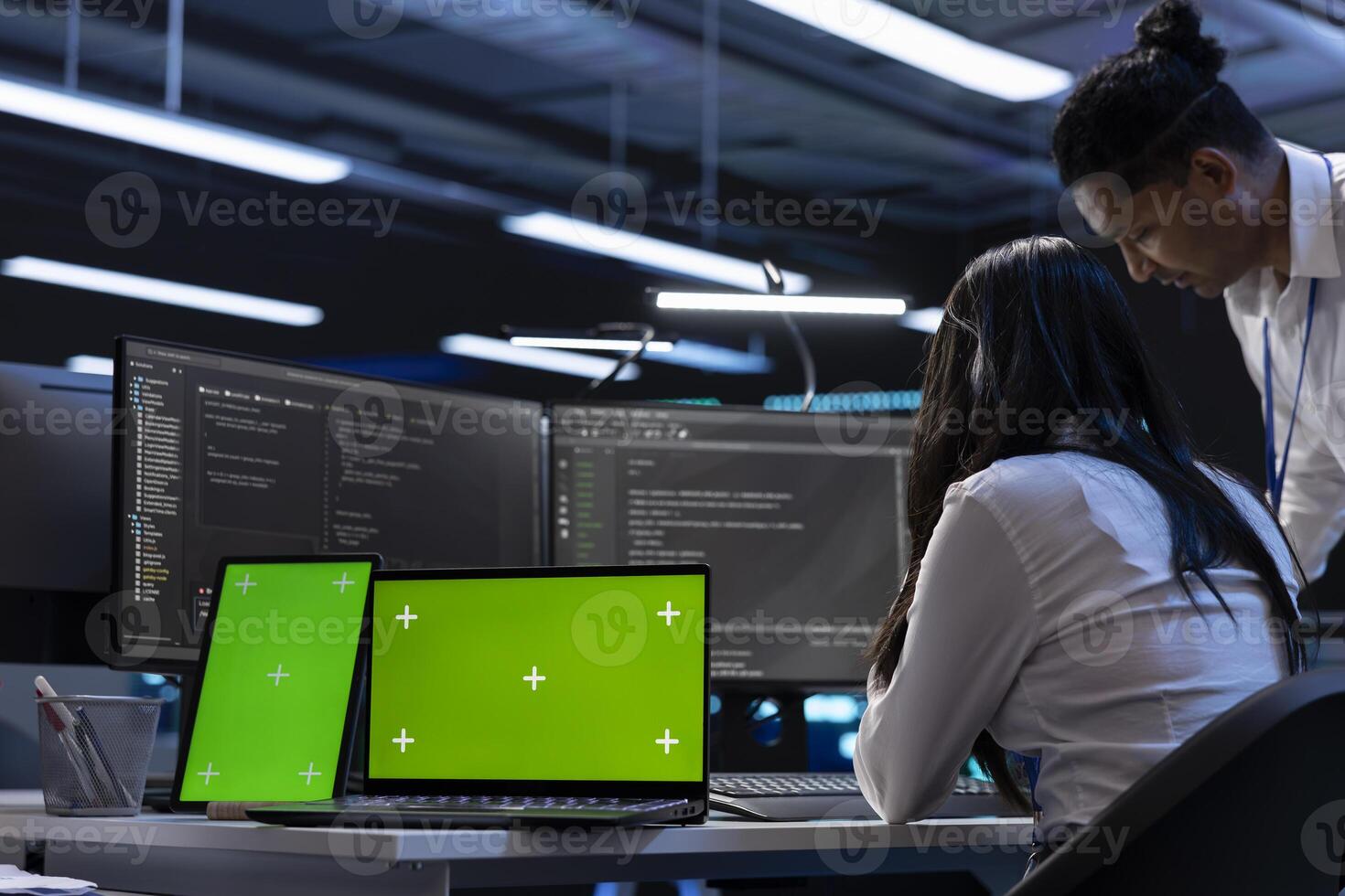Engineers in data center using isolated screen laptop and tablet to find firewall misconfigurations affecting servers. Employees in server room checking systems bottlenecks using chroma key devices photo